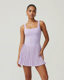 SEEN Essential women's purple pleated tennis dress front view on ghost mannequin showing square neckline and pleated skirt detail.