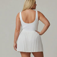 Side profile view of a model wearing the SEEN Essential white tennis dress showing the fitted silhouette and pleated skirt flow.