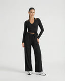Front view of women's black yoga set featuring a long-sleeve wrap top with tie waist and wide leg pants displayed on a ghost mannequin.