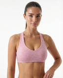 Woman wearing a pink space-dye seamless racerback sports bra with sculpting fit, front view against a white background.