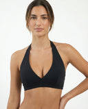 Woman wearing a black halter sports bra with deep V neckline and wide crossover band, front view showing sculpting compression fit.
