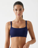 Woman wearing a navy ribbed square neck sports bra crop top with wide straps and compression fit, styled against a white background.