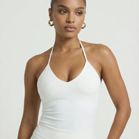 Model wearing a white seamless halter sculpt leggings set with high waist fitted leggings and athletic sneakers.