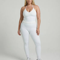 Model wearing a white seamless halter sculpt leggings set with high waist fitted leggings and athletic sneakers.