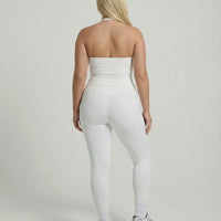 Model wearing a white seamless halter sculpt leggings set with high waist fitted leggings and athletic sneakers.