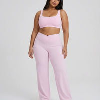Curvy model wearing pink high waist crossover wide leg leggings with matching sports bra, full length front view.