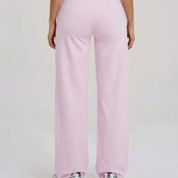 Back view of model wearing pink high waist crossover wide leg leggings, showing V-stitch waistband detail.