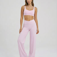 Model wearing pink high waist crossover wide leg leggings with matching sports bra, full length front view