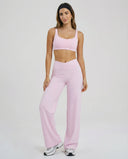 Model wearing pink high waist crossover wide leg leggings with matching sports bra, full length front view